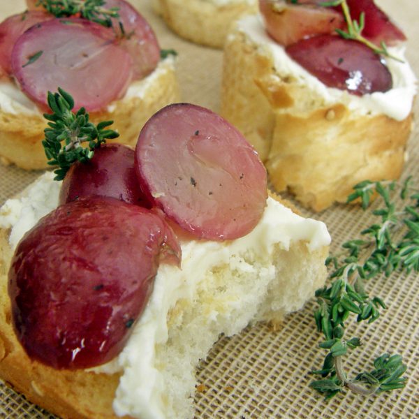 Crostini de queso crema con uvas rojas rostizadas